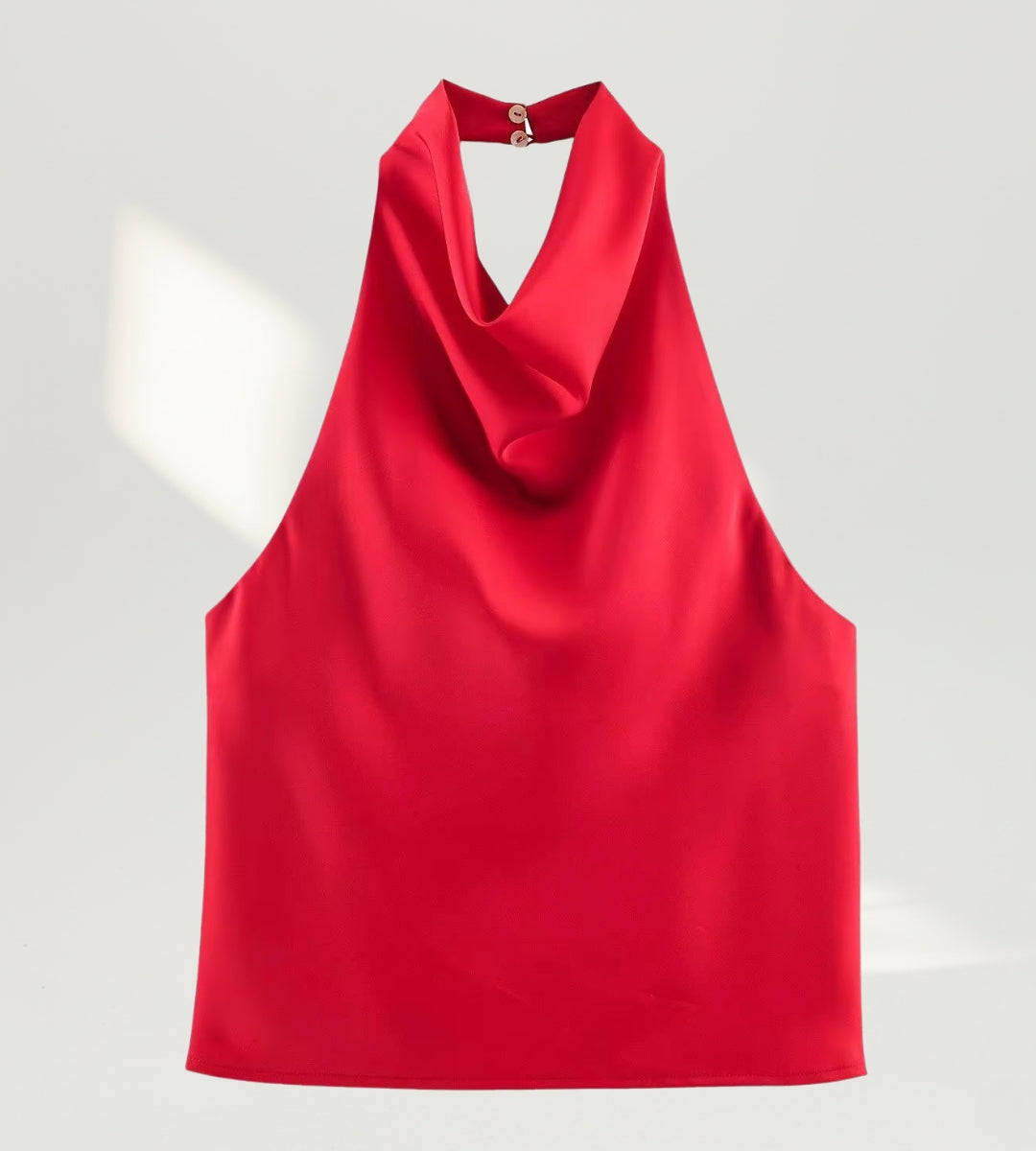 Vista frontal da blusa frente única estilo halter vermelha em cenário de luxo.