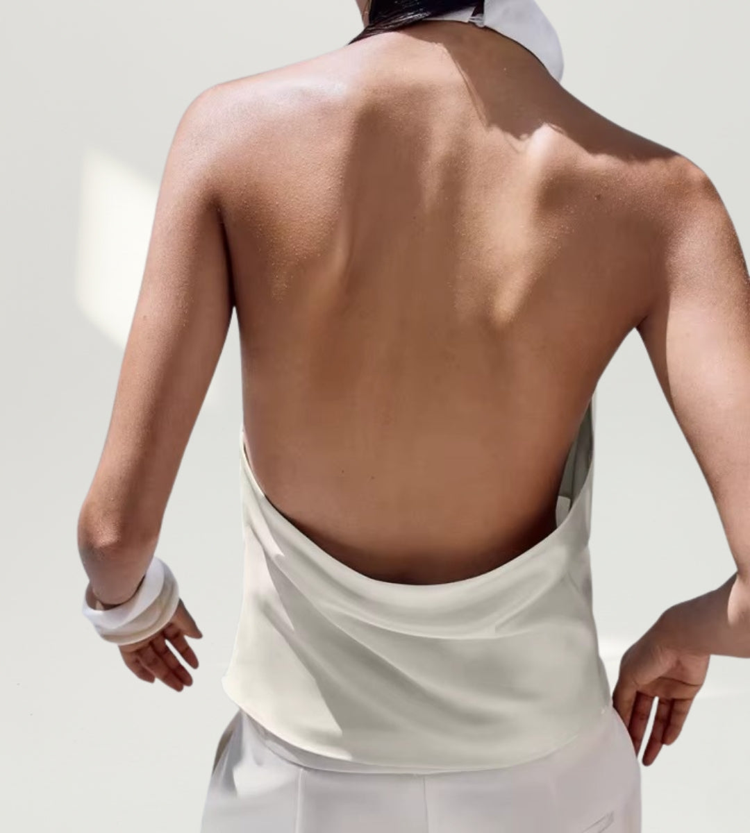 Look feminino de festa com blusa de cetim branca para a moda 2026 em cenário sofisticado.