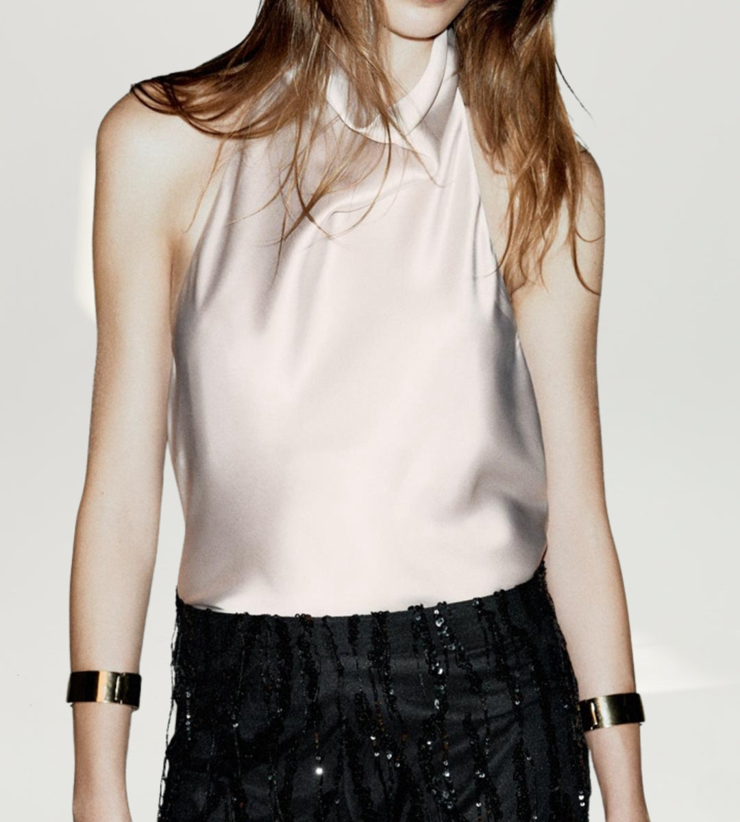 Mulher posando com a blusa champanhe Saybeleze em cenário luxuoso para a moda 2026.