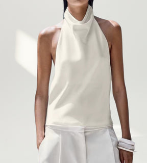 Vista frontal da blusa branca de cetim destacando o movimento fluido do drapeado degagê.