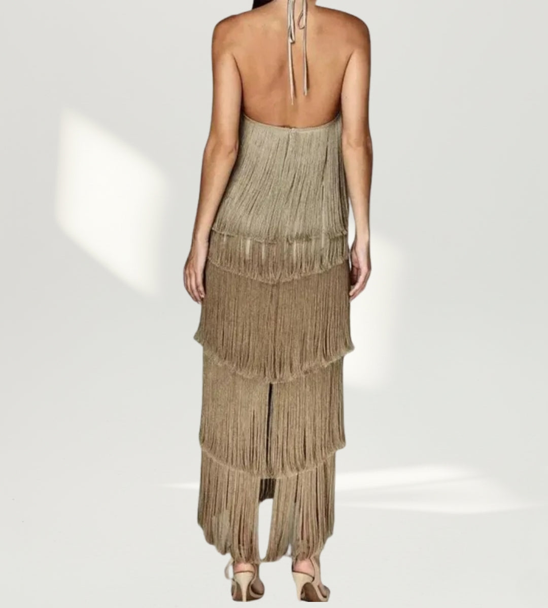 modelo de costas composição de look castanho gala com vestido de franjas e acessórios dourados para eventos noturnos.